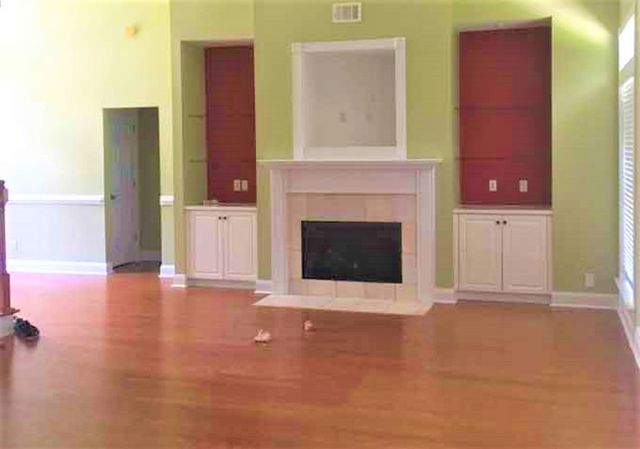 Empty living room with mustard color on the walls, fireplace, and built-ins colored red.