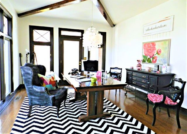 Office-to-living room makeover before with black-and-white rug, dining table, and two mix-matched chairs.
