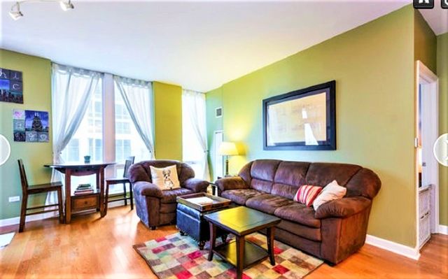 Living room with green walls and outdated sofa and chair before makeover.