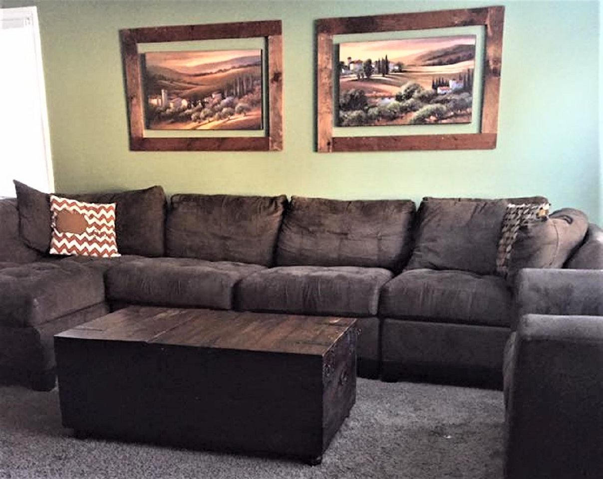 Ranch-style living with dated sectional, trunk, and two framed prints in before makeover