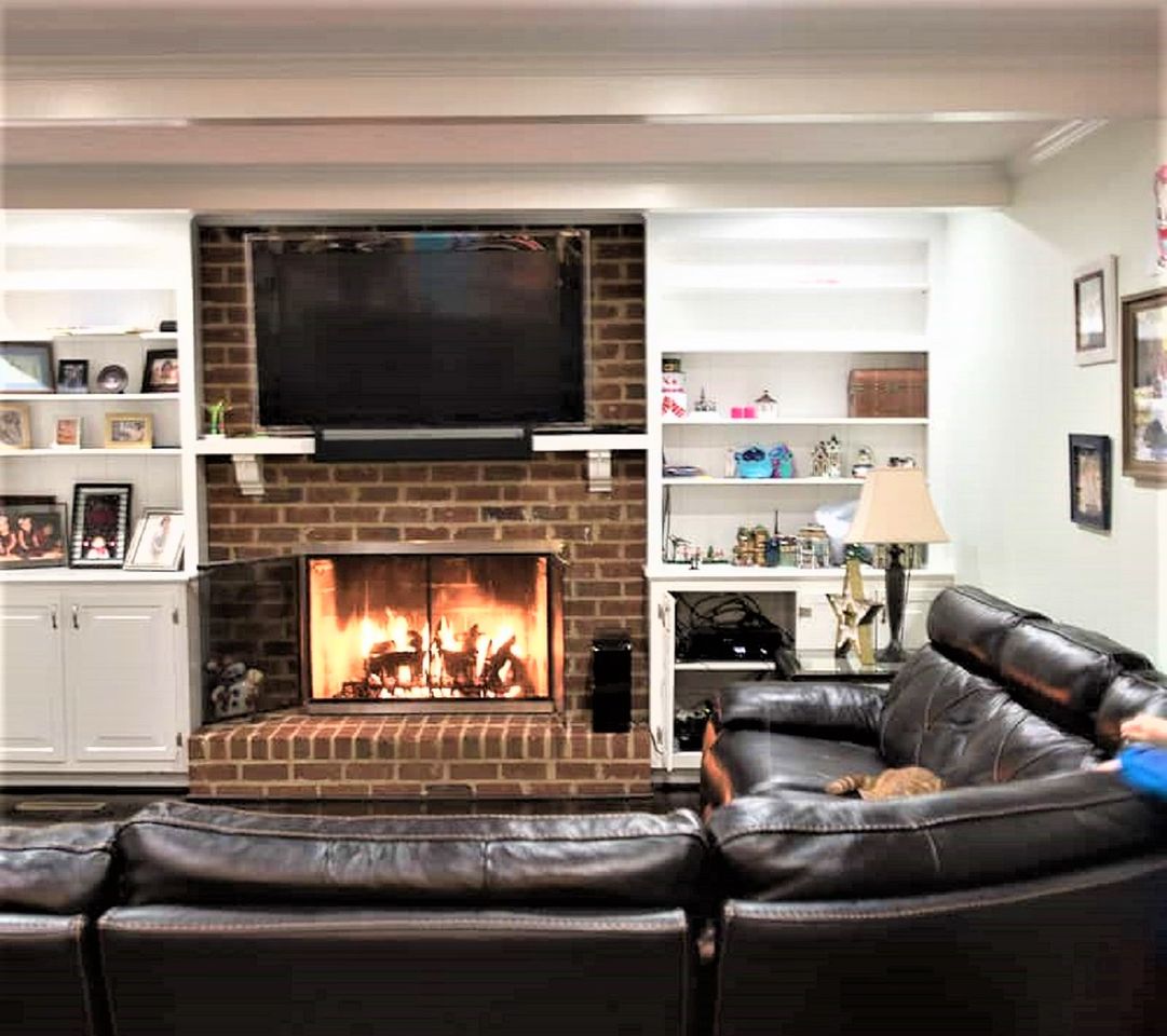 Cozy family style living room with brick fireplace and leather sectional before makeover.