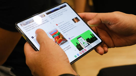A person browses a website on a large folding phone.