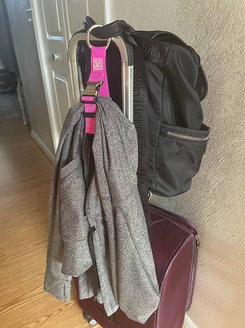 A gray blazer and black backpack are neatly draped over a suitcase, ready for travel
