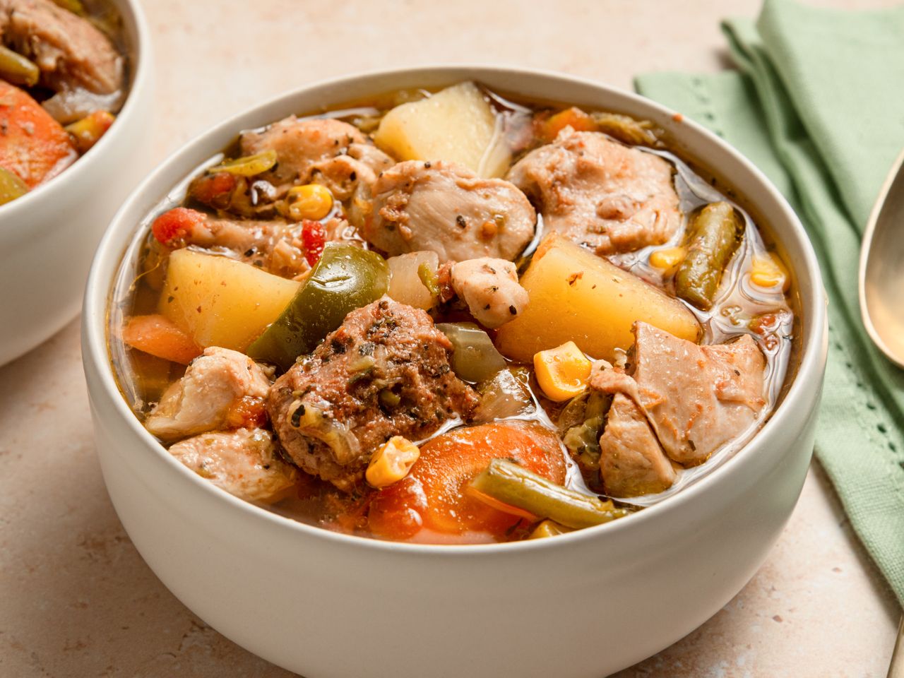 A bowl of chicken booyah containing assorted vegetables and chunks of chicken