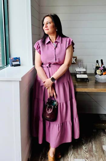Woman in a tiered dress with ruffled sleeves stands by a window next to a table with champagne bottles in an ice bucket