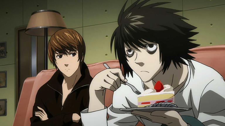 Light Yagami and L sitting on a couch, as Light watches L enjoy a sugary treat in Death Note