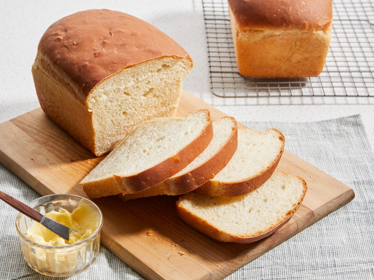 high angle looking at Amish white bread on a cutting board with a few slices cut, next to butter in a bowl