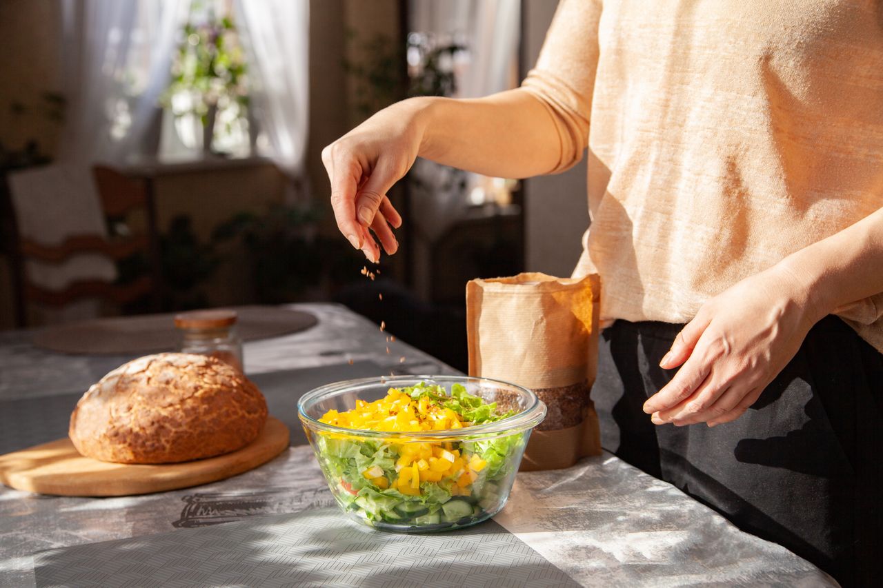 Woman adding seeds to a salad bowl