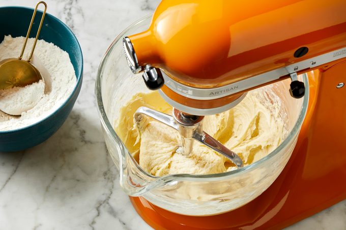 Overhead view of peach cookie dough fully mixed in a stand mixer bowl, showing a smooth, pale dough consistency.