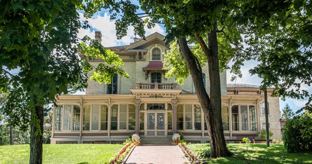 The historic Villa Louis mansion in Prairie du Chien, WI, a Victorian estate framed by summer trees.