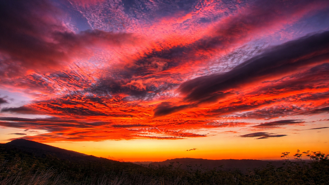 Dramatic red sunset sky with vibrant clouds over mountains