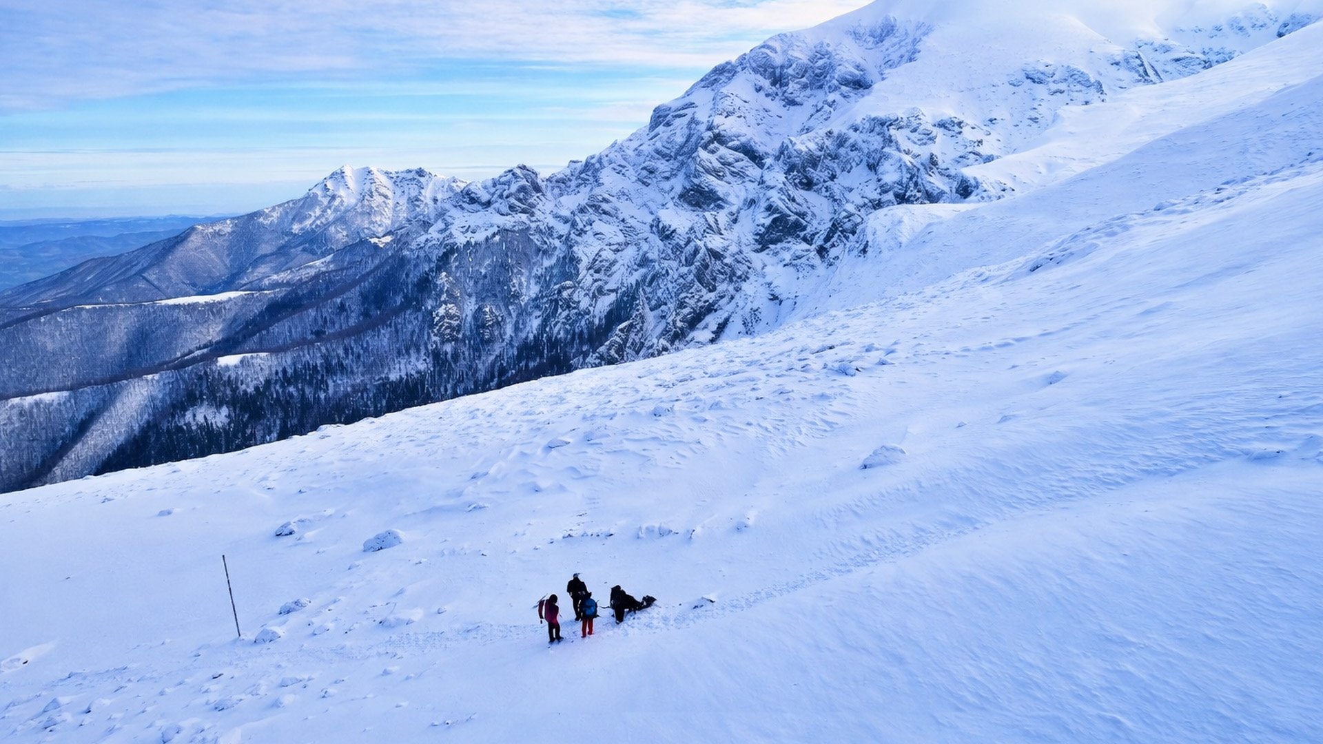 Botev Peak covered in snow with climbers crossing the ridge