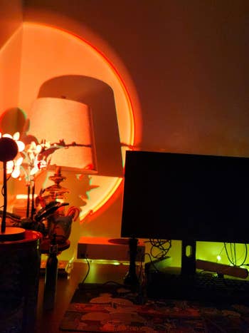 A desk setup with a computer monitor and decorative lamp casting artistic shadows on the wall