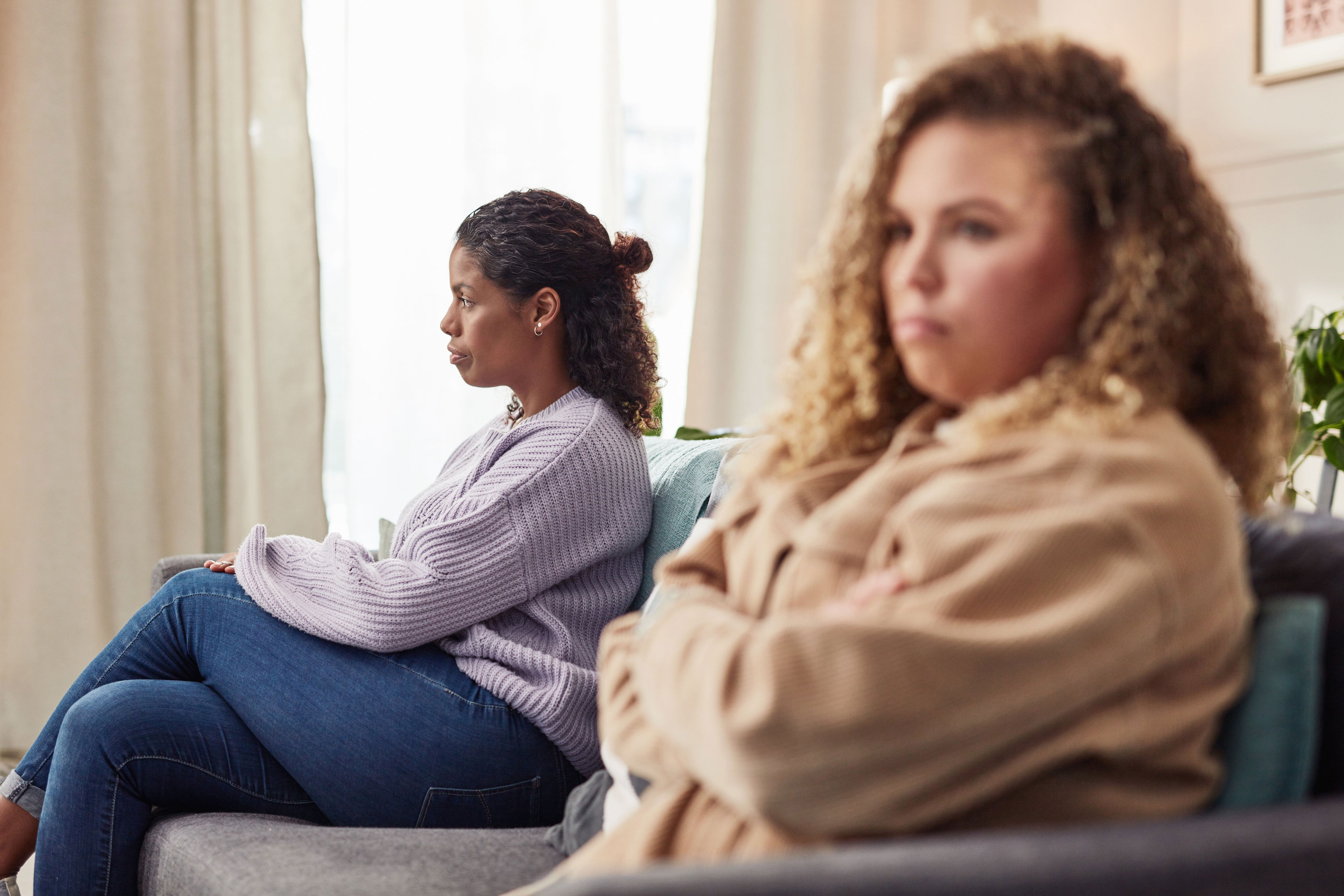 Two people sitting on a couch looking away from each other, appearing upset or contemplative