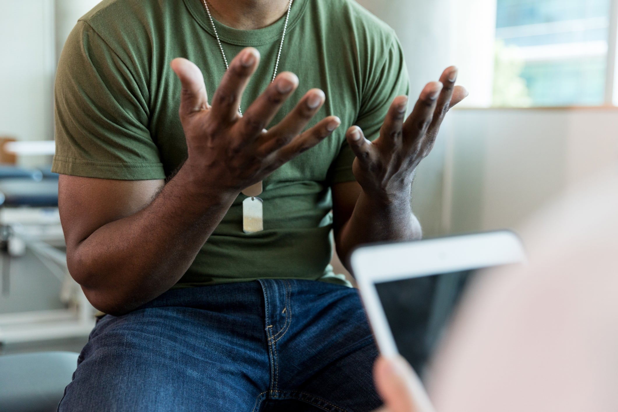 Person in a casual outfit gesturing with hands during a conversation, seen from the waist up, possibly explaining something