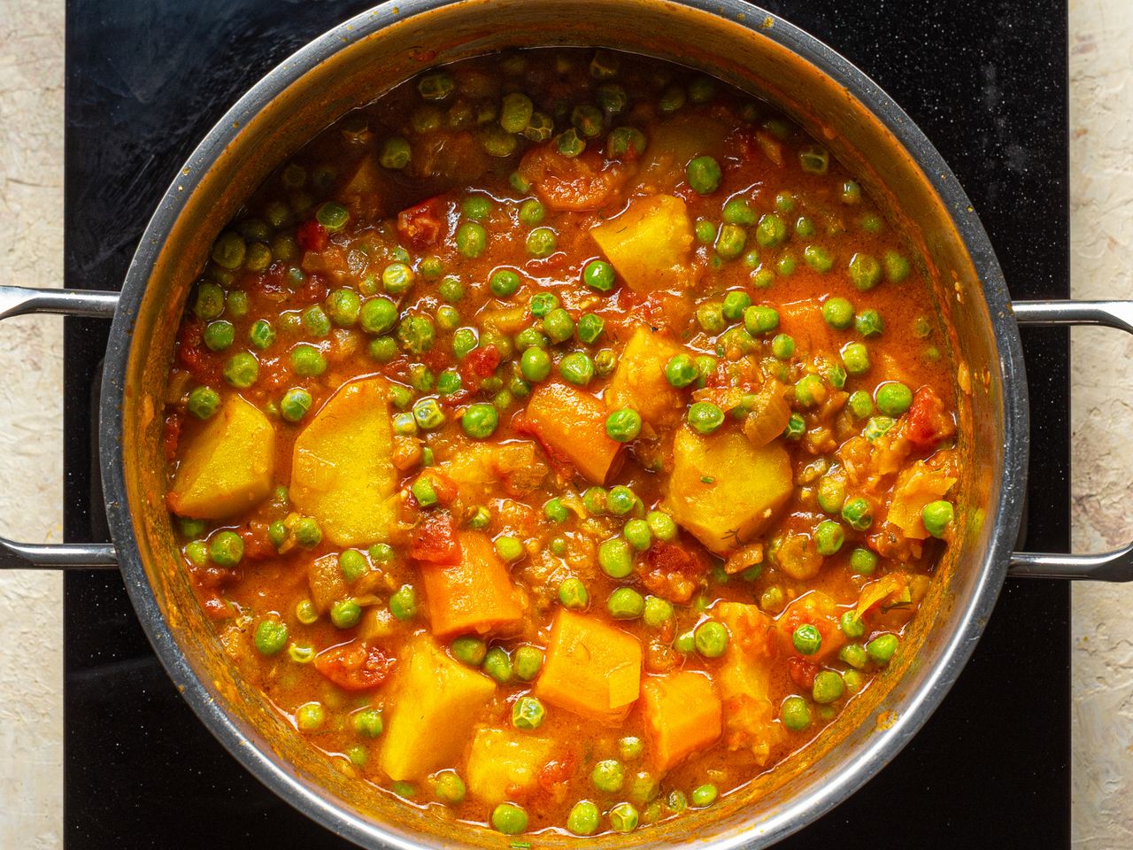 A pot of cooked peas potatoes and other vegetables
