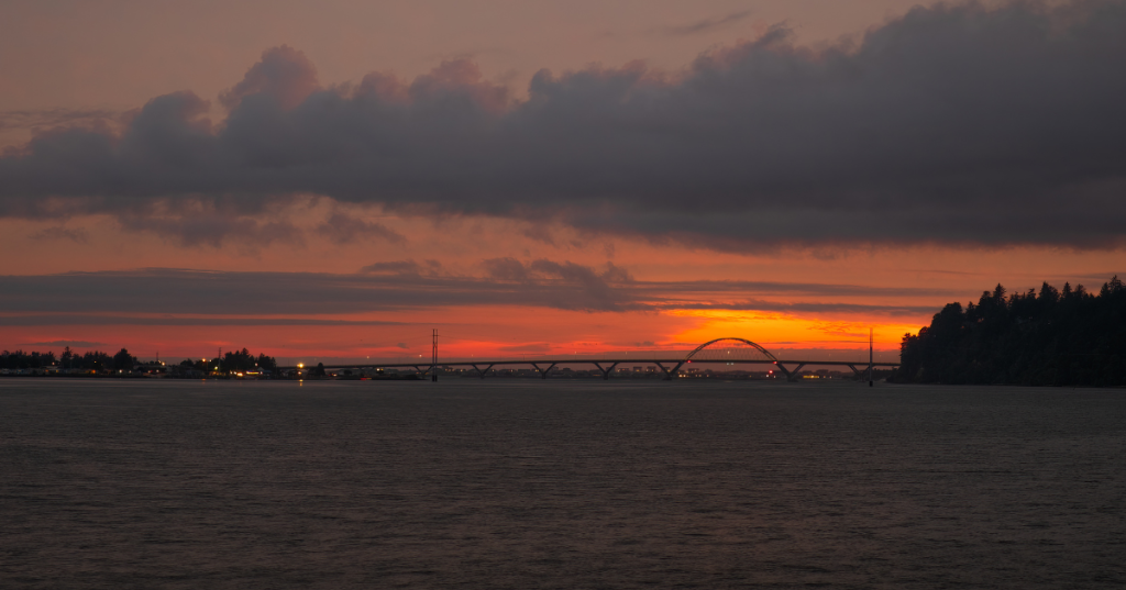 A fiery sunset lights up the sky above Waldport, Oregon, and the Alsea Bay Bridge.