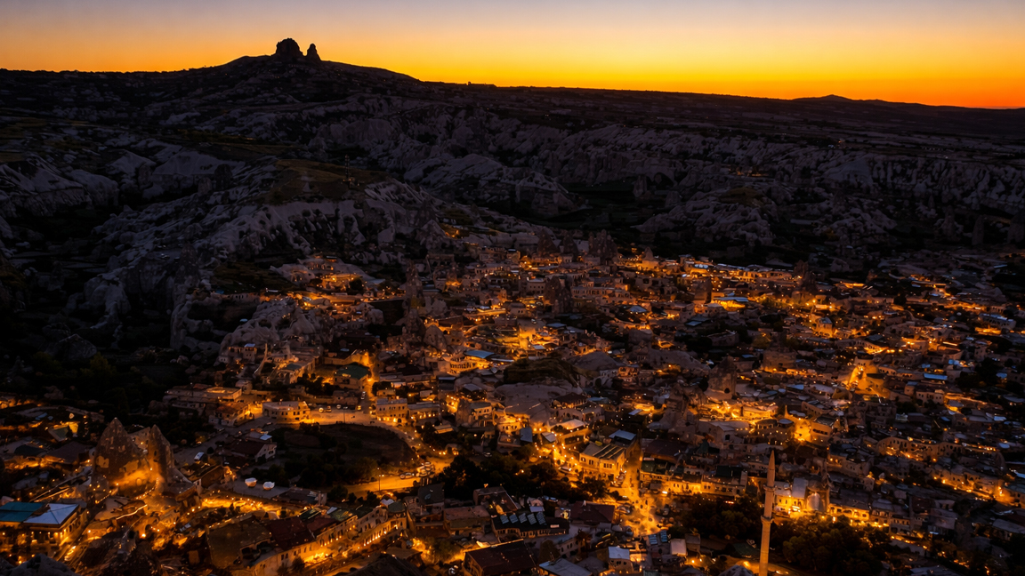 Luces de la ciudad al atardecer brillando en un valle de montaña