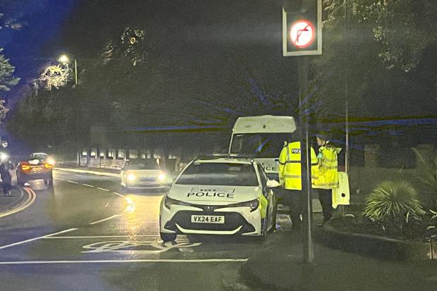 Police car and van block city road following incident