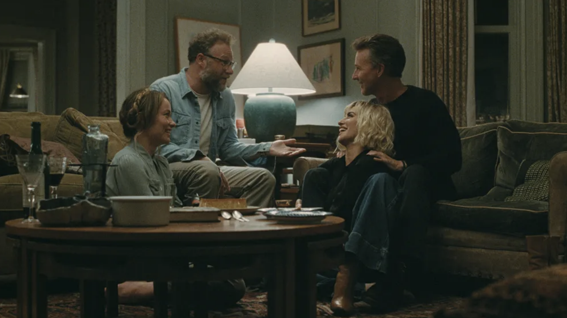 Olivia Wilde, Seth Rogen, Edward Norton, and Pénelope Cruz sit talking in a living room.