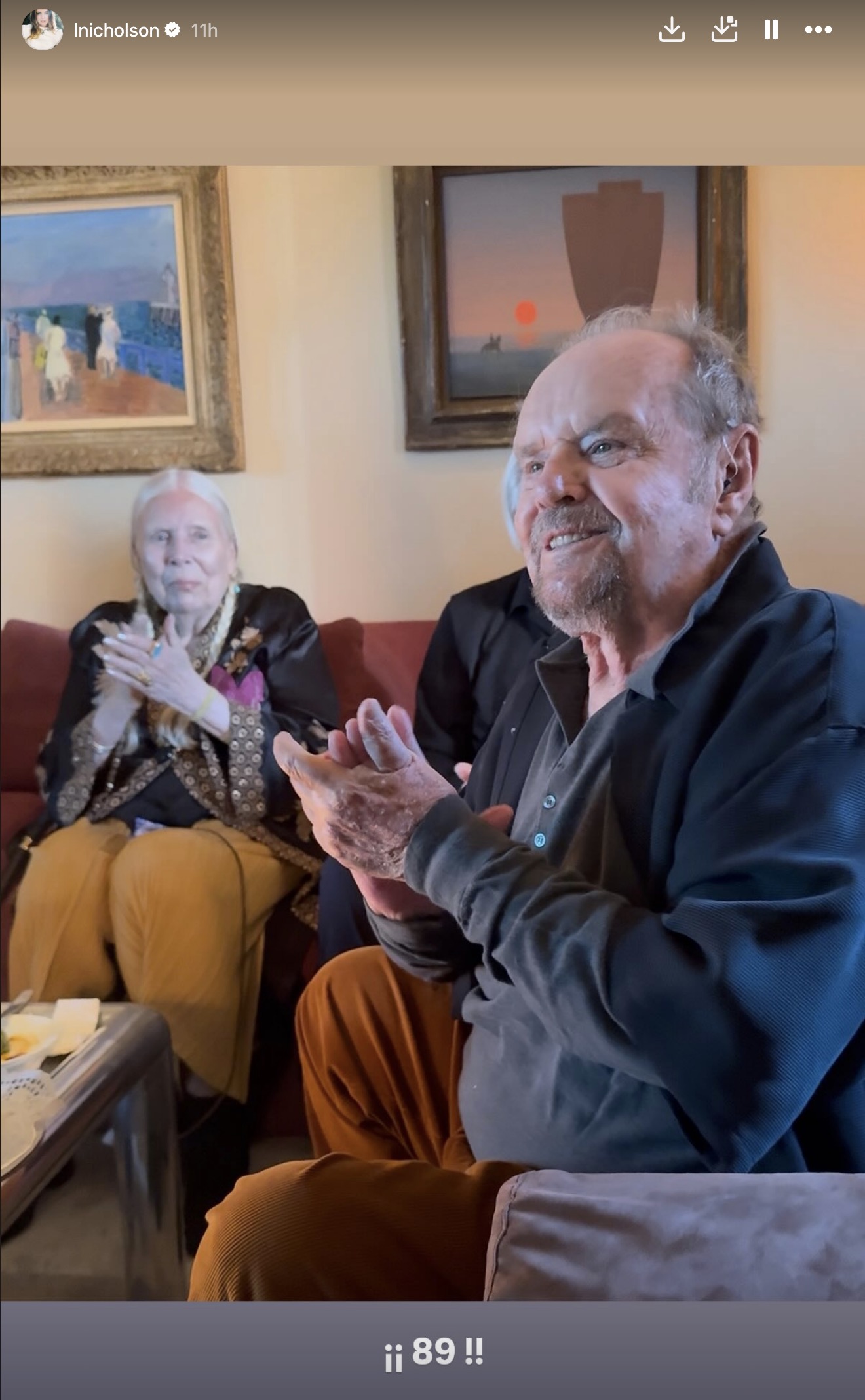 Jack Nicholson and another individual sitting on a couch, clapping.