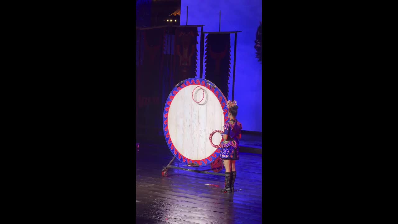 Woman and knife thrower create coordinated hoop display on stage in ...