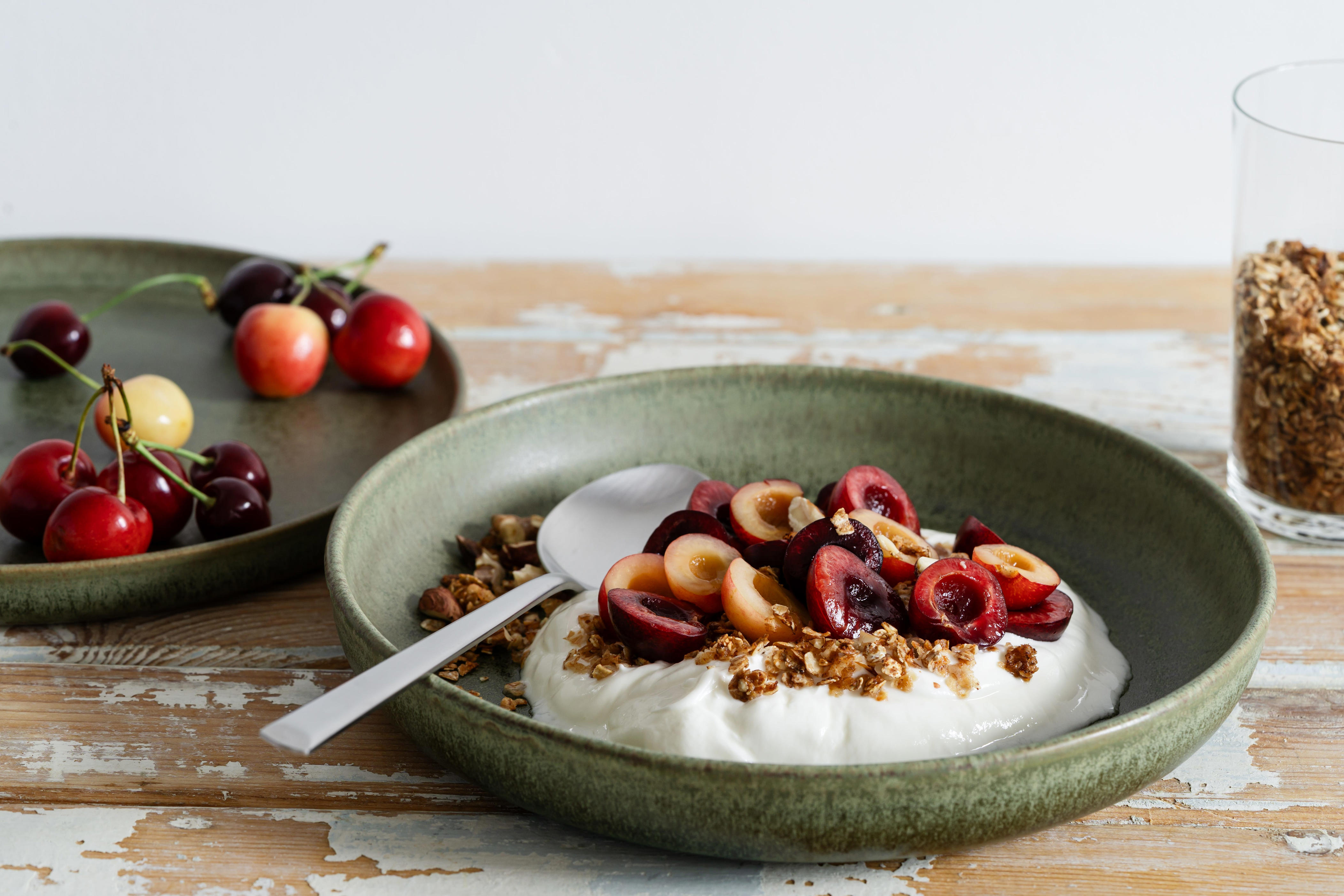 A bowl of Greek yogurt with cherries and granola.