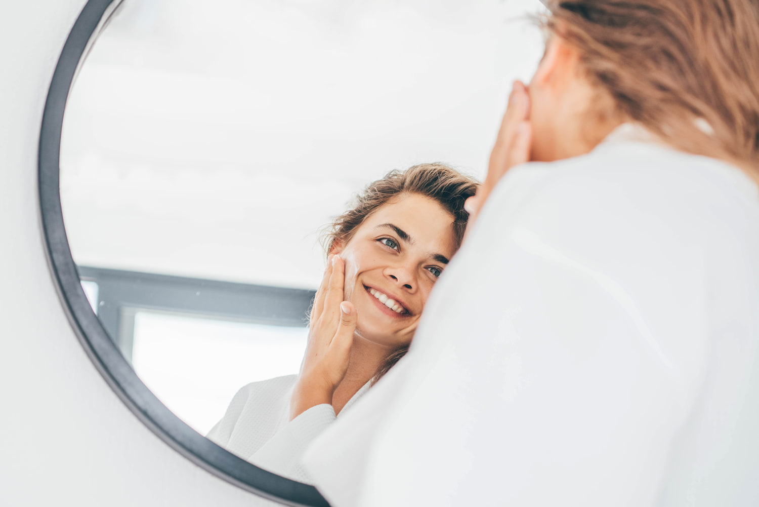 Woman enjoys routine applying moisturizing cream on face