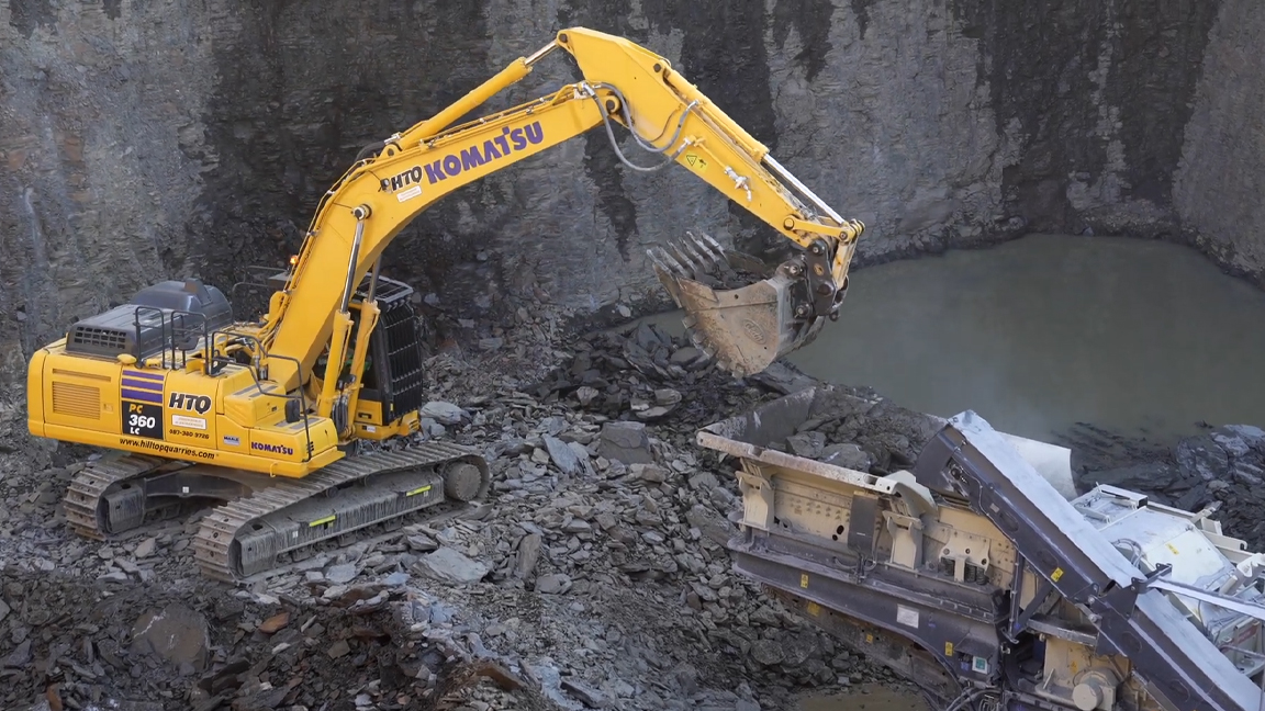 Giant excavator crushing rocks in quarry operation