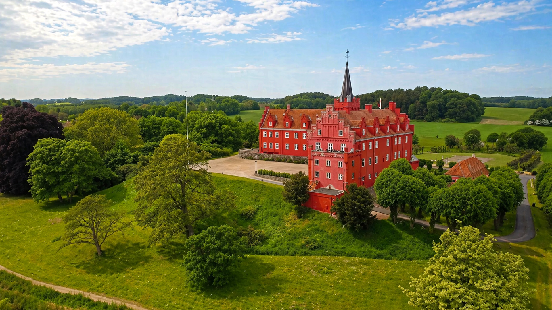 A bright red castle standing out in a green landscape