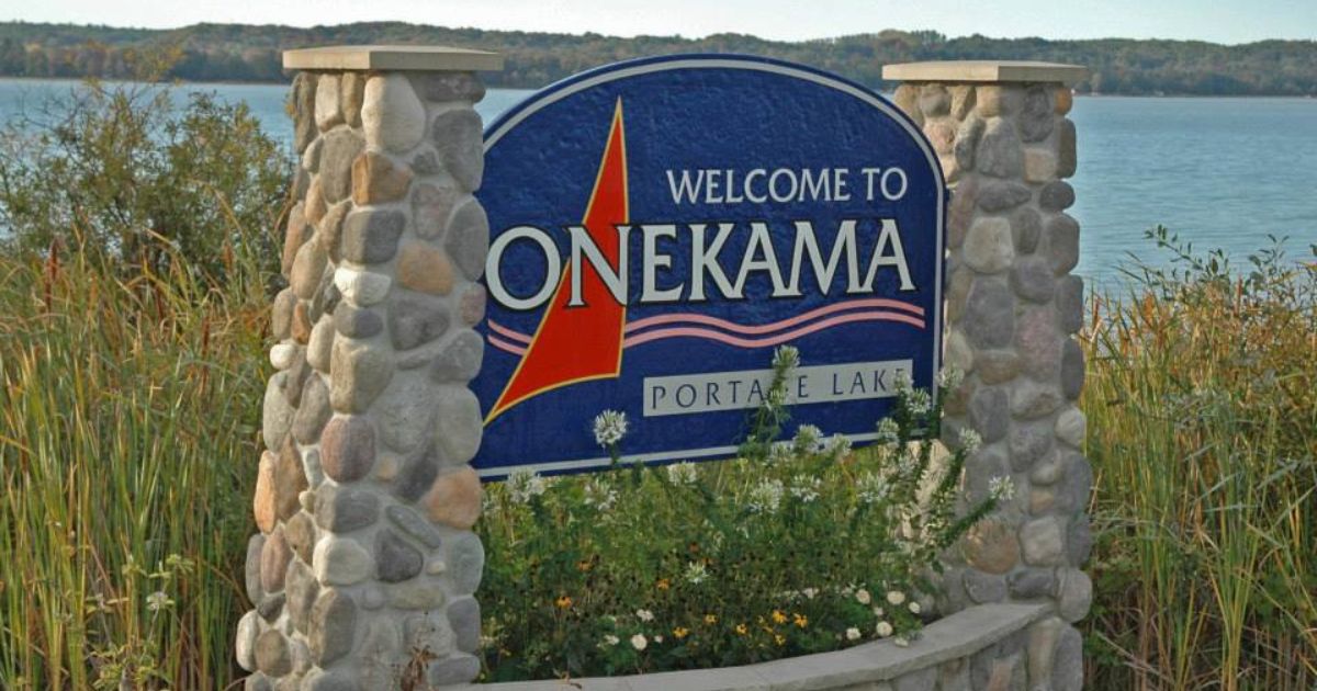 Welcome sign to Onekama, Michigan, with the lake in the background