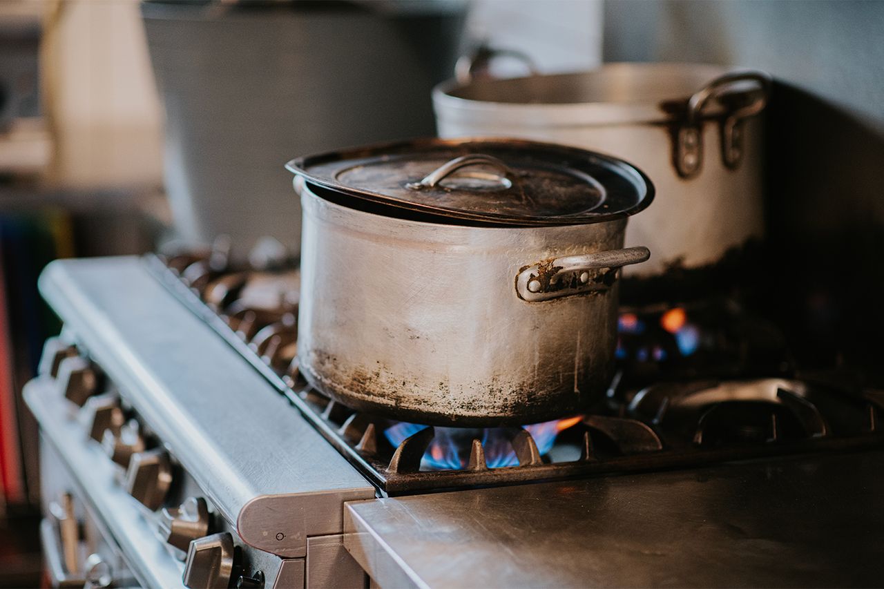 Two cooking pots on a stovetop with visible flames underneath