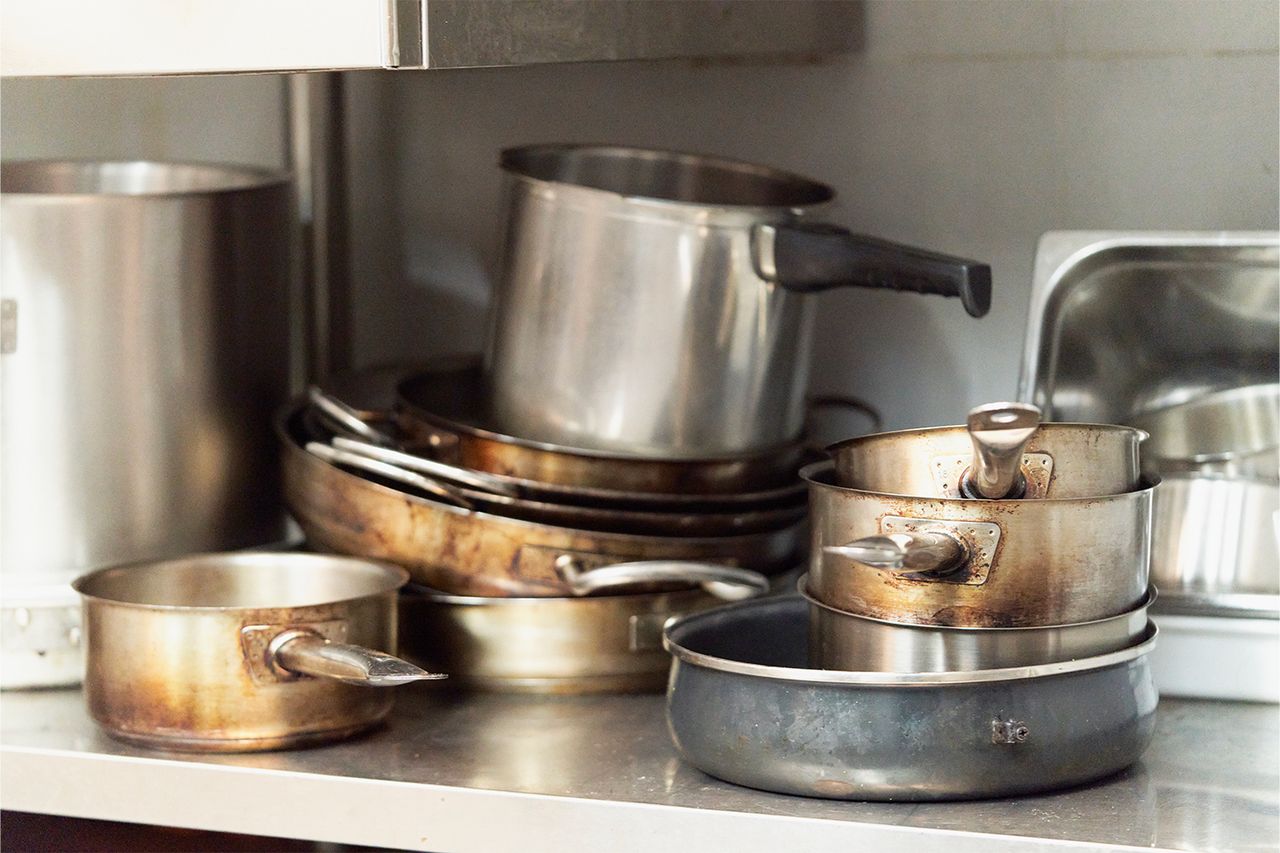 A collection of used pots and pans stacked on a kitchen counter