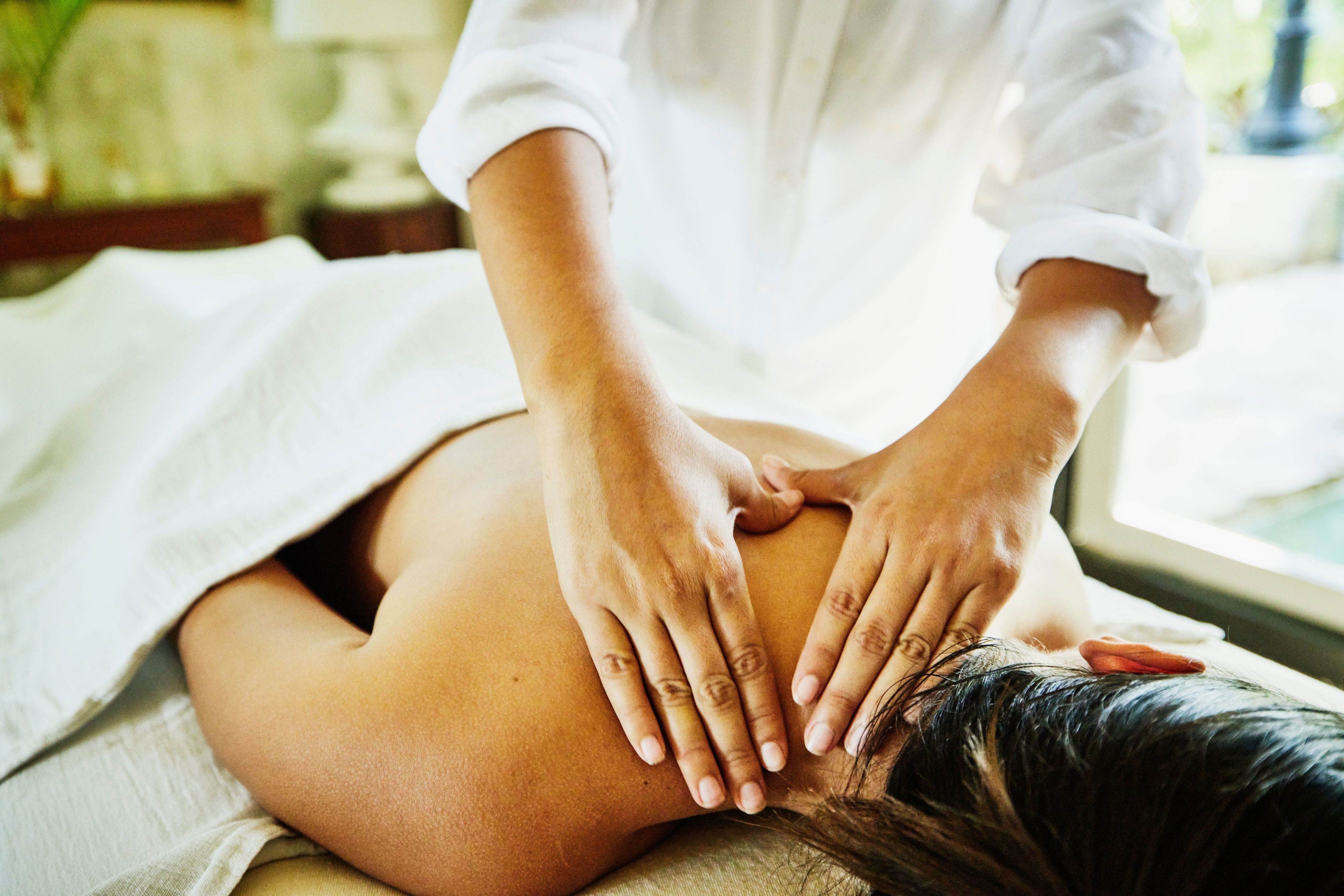 Person receiving a massage in a serene setting, emphasizing relaxation and wellness, suitable for a work-life balance context