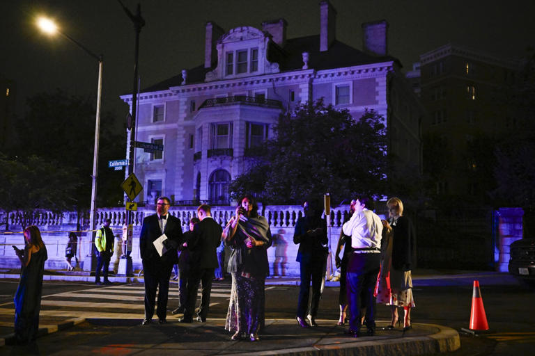 Guests make calls and check their phones outside the Washington Hilton.