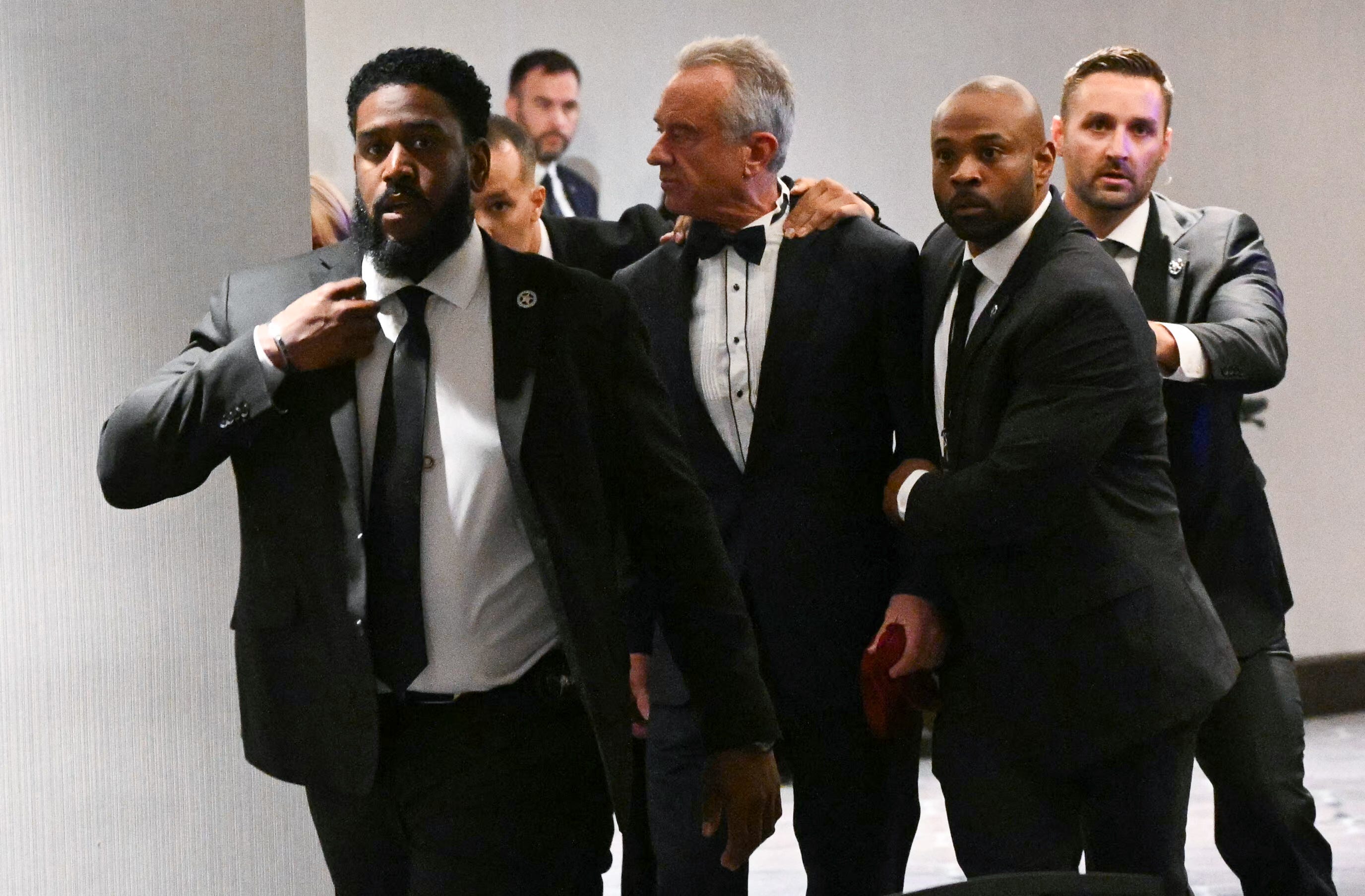 TOPSHOT - US Secretary of Health and Human Services Robert F. Kennedy Jr. is rushed out by Secret Service agents after loud bangs were heard during the White House Correspondents' dinner at the Washington Hilton in Washington, DC, on April 25, 2026. President Trump is attending the annual gala of the political press for the first time while in office. (Photo by Mandel NGAN / AFP via Getty Images)