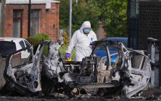 Forensic investigators examine the wreckage after a car bomb exploded outside a police station in Northern Ireland