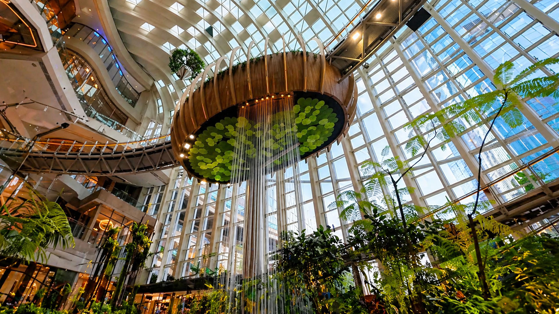 A glass roof mall with hanging water feature and greenery
