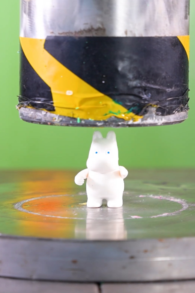 Hydraulic press crushing small toy figure