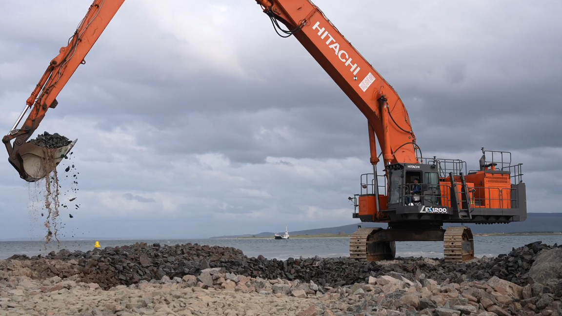 Giant excavator moving heavy materials by the sea