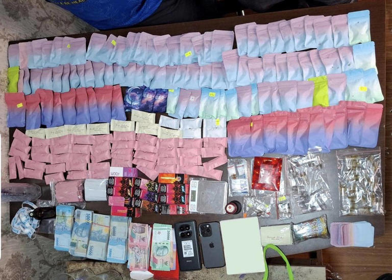 Barang bukti berupa ratusan kantong berwarna gradasi, uang tunai, ponsel, dan catridge etomidate yang ditemukan polisi di atas meja.