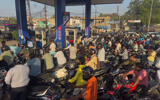 Commuters wait in long queues for fuel at a petrol station in Prayagraj, India - Rajesh Kumar Singh/AP