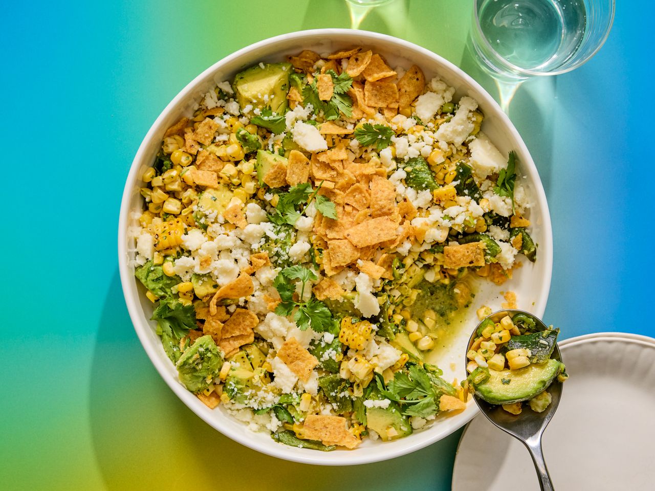 A bowl of corn salad with various toppings, photographed with vibrant background colors