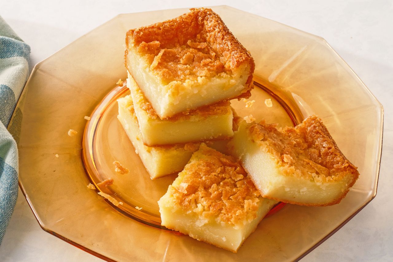 A plate with stacked pieces of butter mochi a Hawaiian dessert