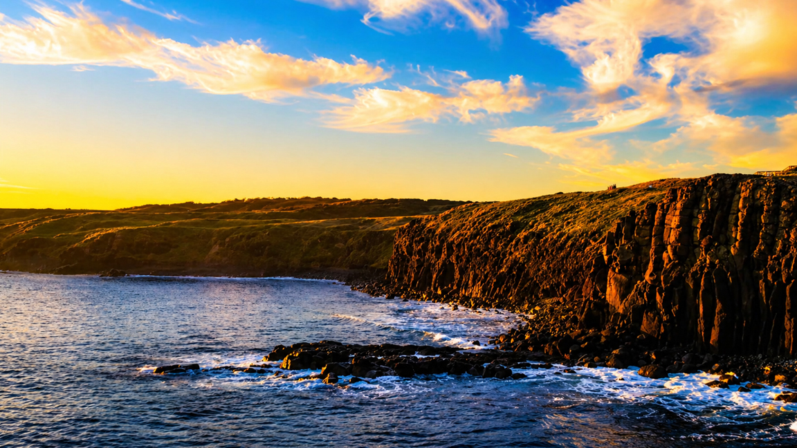 Golden sunset over rocky coastal cliffs and ocean waves
