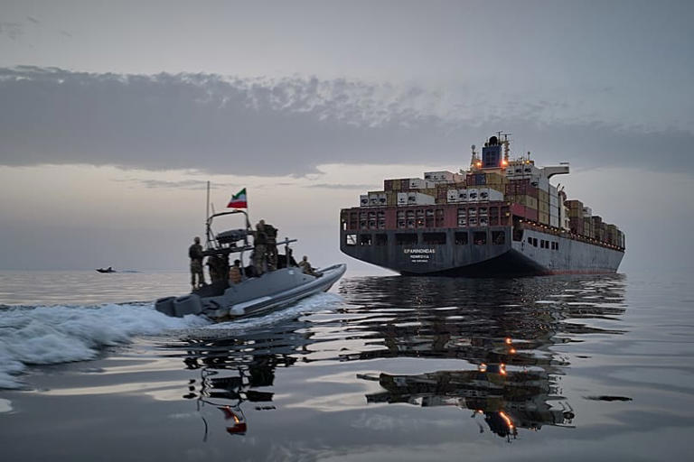 An Iranian Revolutionary Guard speedboat approaches a cargo vessel in the Strait of Hormuz. Meysam Mirzadeh/Tasnim News Agency via AP