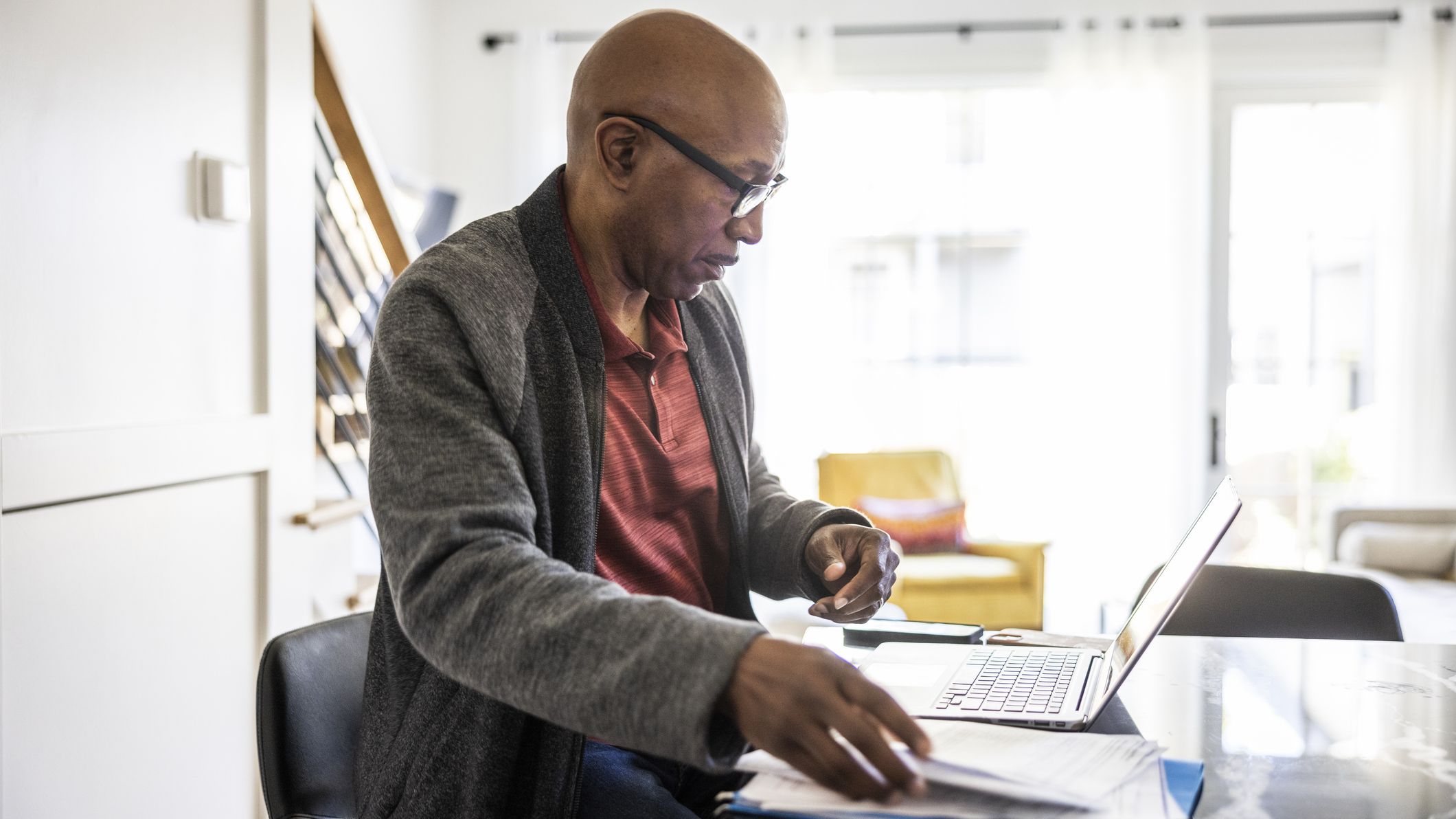 Senior man using laptop and paying bills at home