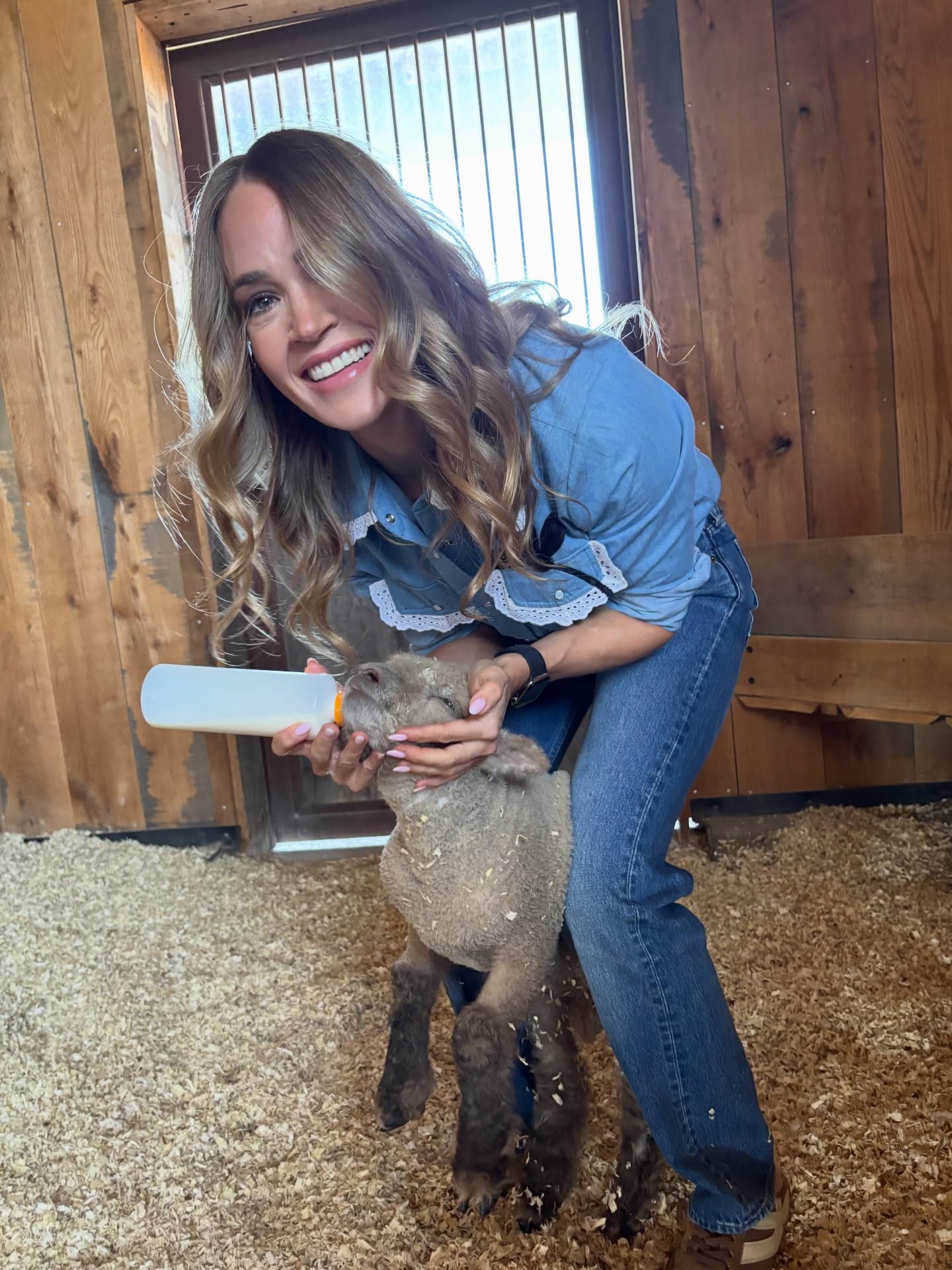 Carrie Underwood feeding a lamb from a bottle.