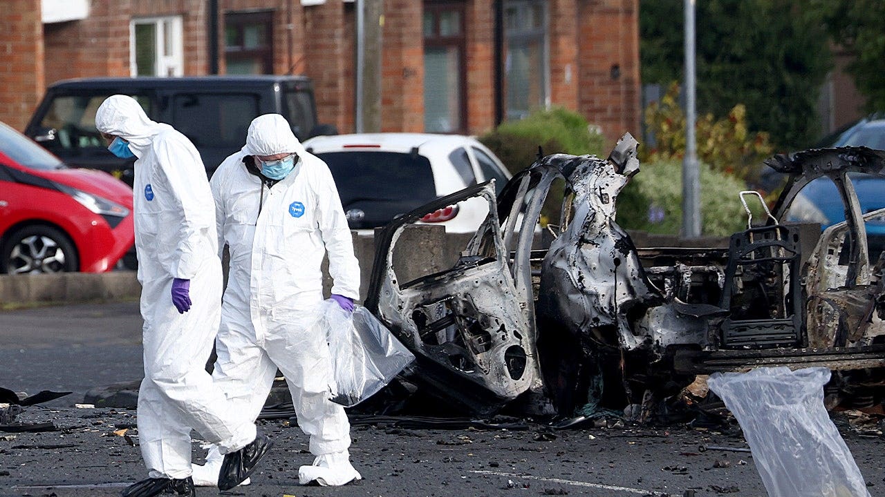 Forensic investigators inspect the site of a car bomb that exploded outside Dunmurry police station in South Belfast,