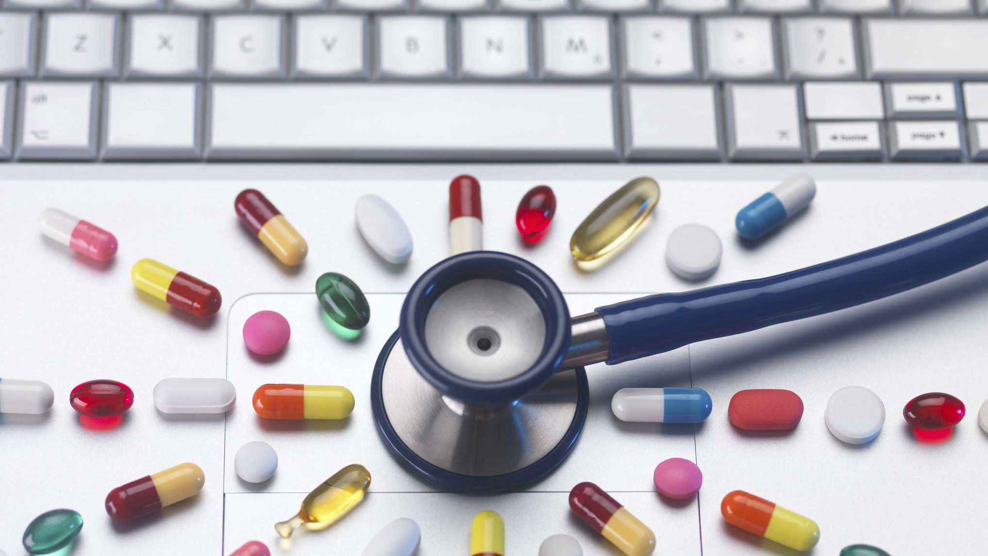 Pills and stethoscope on laptop